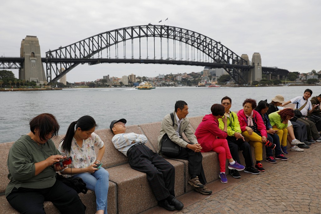 Chinese tourists rest near the Harbour Bridge in Sydney. In 2020, 65 per cent of Chinese-Australians felt connected to China, but that figure declined to 56 per cent in 2022. Photo: Reuters