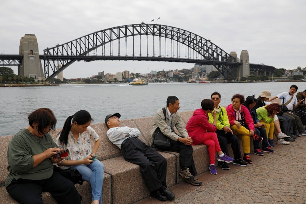 Chinese tourists rest near the Harbour Bridge in Sydney. In 2020, 65 per cent of Chinese-Australians felt connected to China, but that figure declined to 56 per cent in 2022. Photo: Reuters