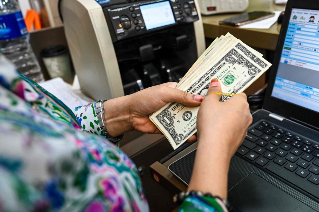 US dollar notes being counted out at a money changer booth at the Raffles Place financial business district in Singapore. The outsize role of the US dollar in global finance makes it a potent, yet possibly destructive, force. Photo: AFP