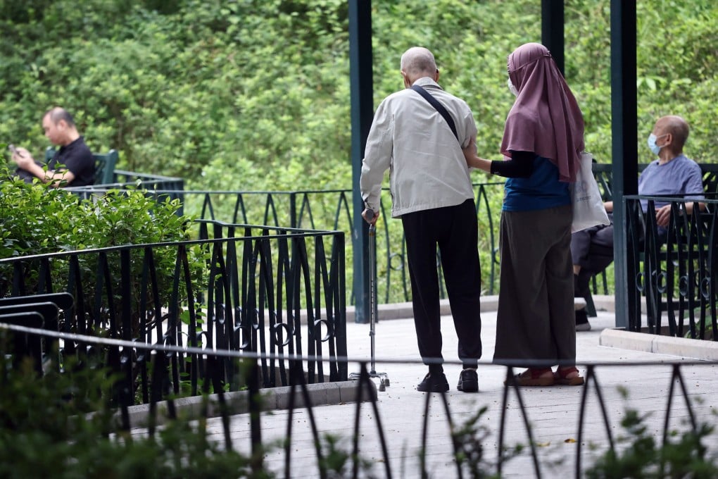 A domestic worker walks with an elderly man in a garden in Jordan in 2022. Photo: K.Y. Cheng