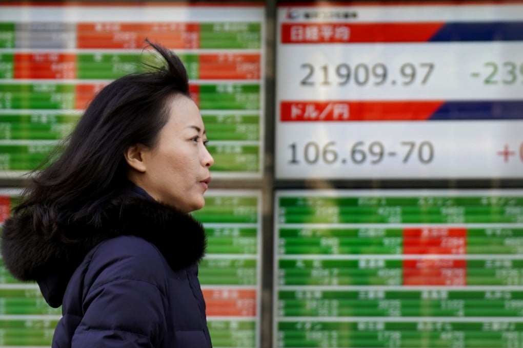 A woman walks past an electronic stock indicator in Tokyo, Japan. File photo: AP