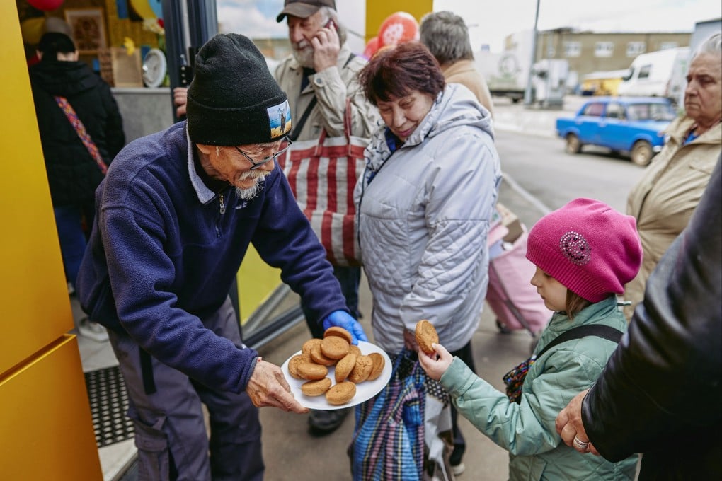 Fuminori Tsuchiko treats a girl with cookies outside of his cafe in Kharkiv, Ukraine on Monday. Photo: Reuters