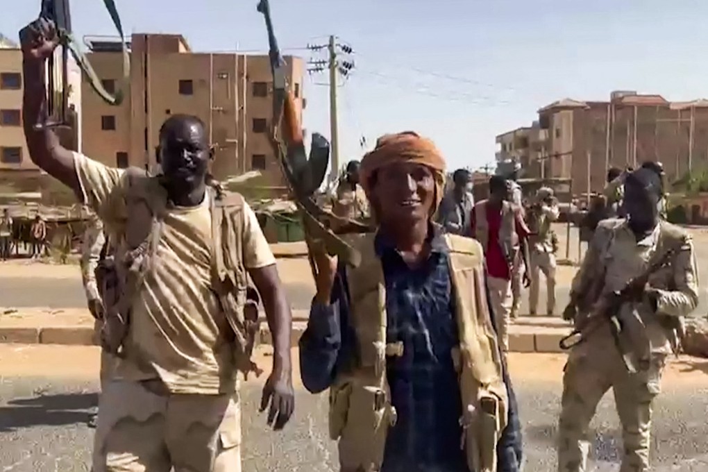 Rapid Support Forces fighters wave assault rifles as they cross a street in the East Nile district of greater Khartoum in footage released on Sunday. Photo: Rapid Support Forces via AFP