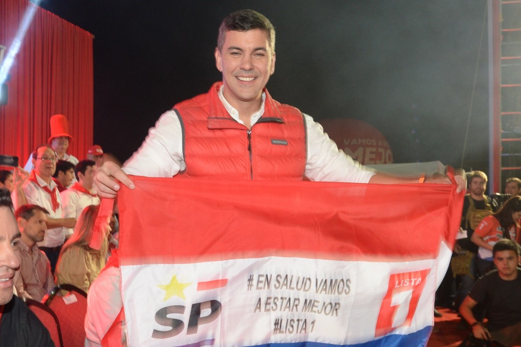 Santiago Pena, the Paraguay presidential candidate of the ruling Colorado Party, holds a banner while campaigning in Asuncion on Thursday. Photo: EPA-EFE