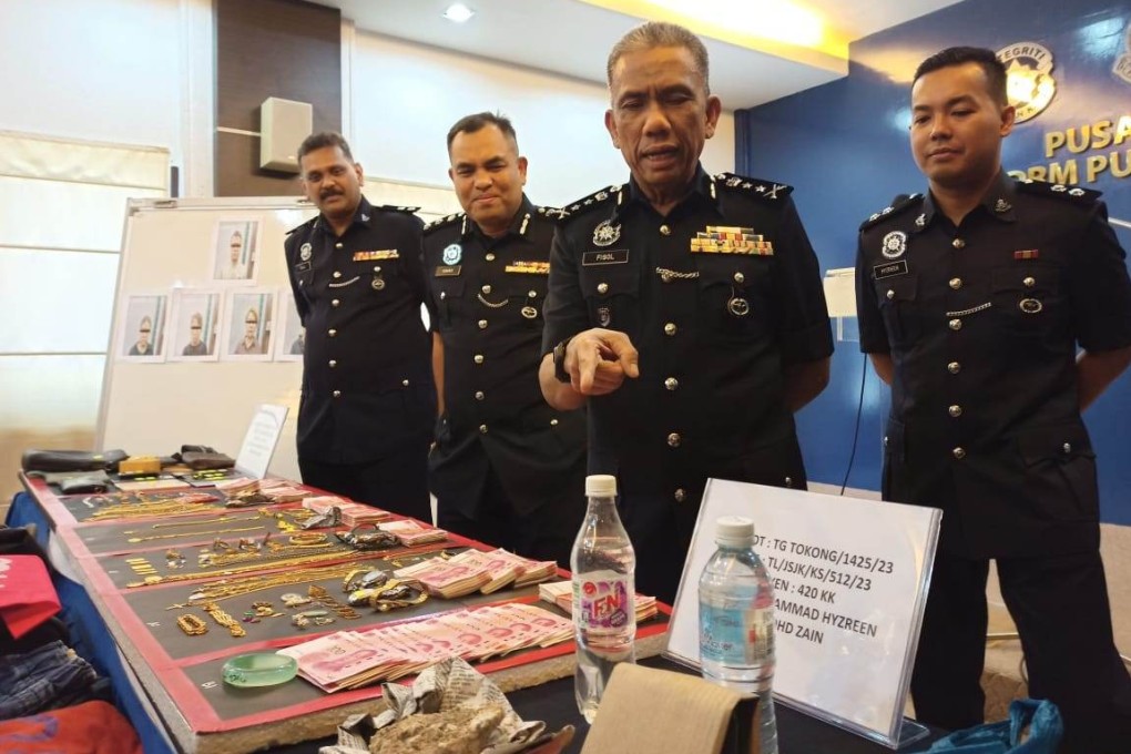 Fisol Salleh, deputy police chief of Penang state, draws attention to the cash and other items that were confiscated from the scam syndicate’s members. Photo: Facebook/PolisPulauPinang