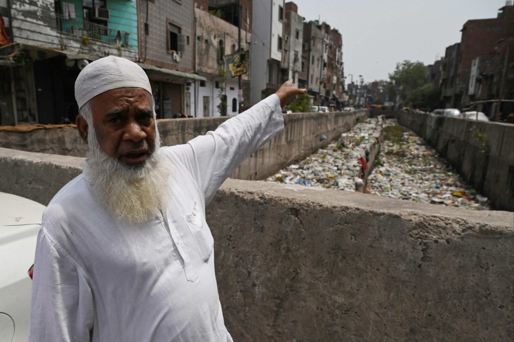 Resident Khalil Ahmad gestures next to a storm drain clogged with sewage and garbage in the Seelampur neighbourhood of New Delhi. He said the filth keeps making children in the area sick. Photo: AFP