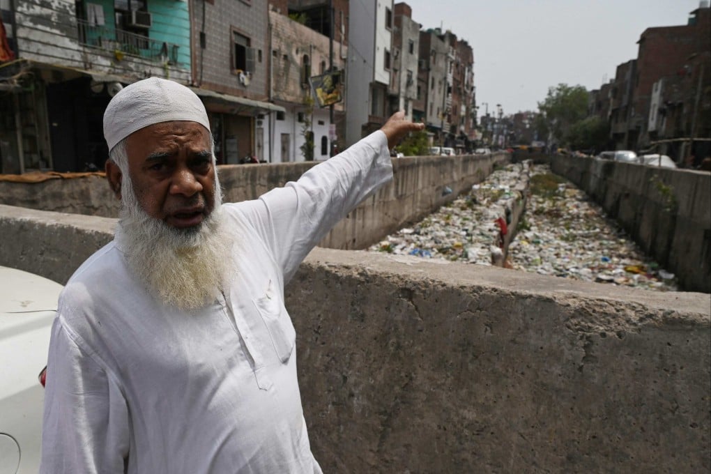 Resident Khalil Ahmad gestures next to a storm drain clogged with sewage and garbage in the Seelampur neighbourhood of New Delhi. He said the filth keeps making children in the area sick. Photo: AFP