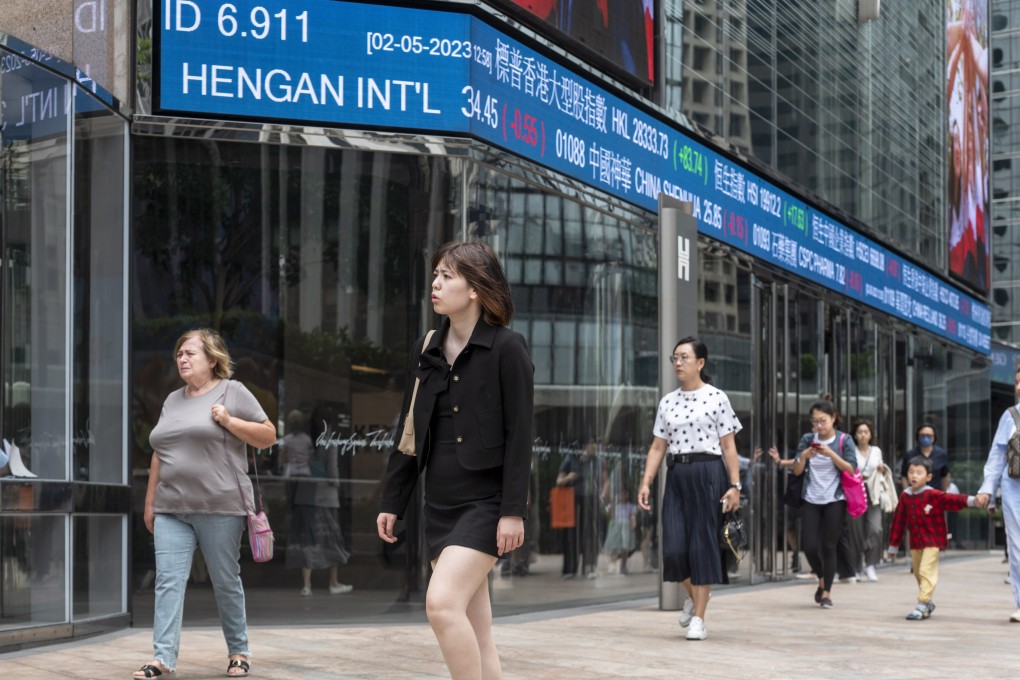 Pedestrians walk past a stock ticker outside Exchange Square, the building housing the stock exchange in Hong Kong on May 2, 2023. Photo: EPA-EFE