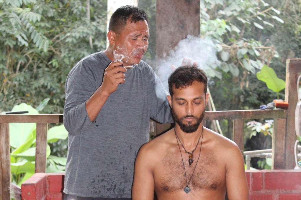 A shaman (right) performs an indigenous energy-clearing ritual on one of the study leaders. The research aims to determine if psychedelic plants can be used to treat mental health conditions. Photo: Ayahuasca Foundation