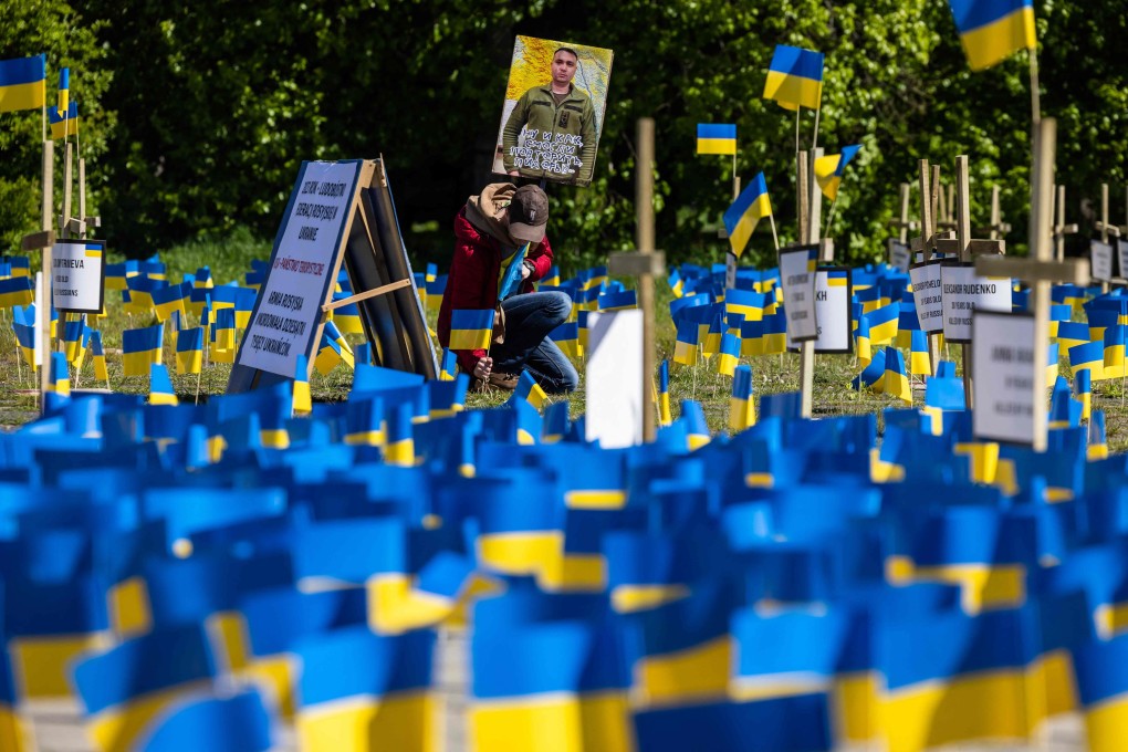 A man plants a Ukrainian flag amid other flags and crosses with the names of victims, during a protest organised by Ukrainian diaspora activists in Poland on Tuesday, the 78th anniversary of the victory over Nazism and the end of World War II in Europe. Photo: AFP
