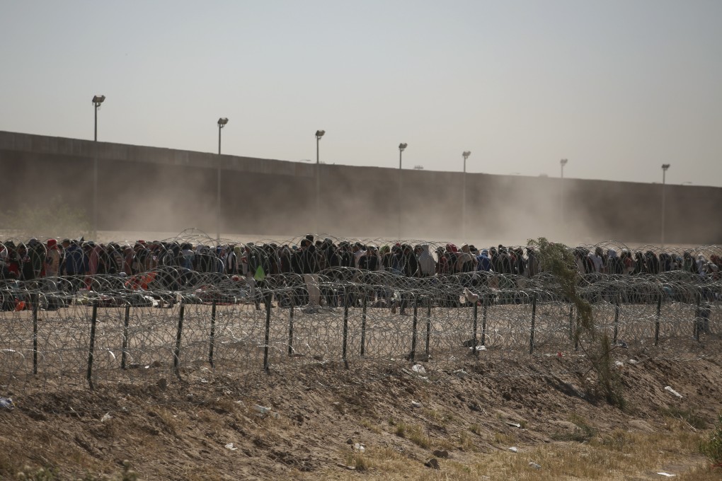 Migrants line up between a barbed-wire barrier and the border fence at the US-Mexico border, as seen from Ciudad Juarez, Mexico. Photo: AP