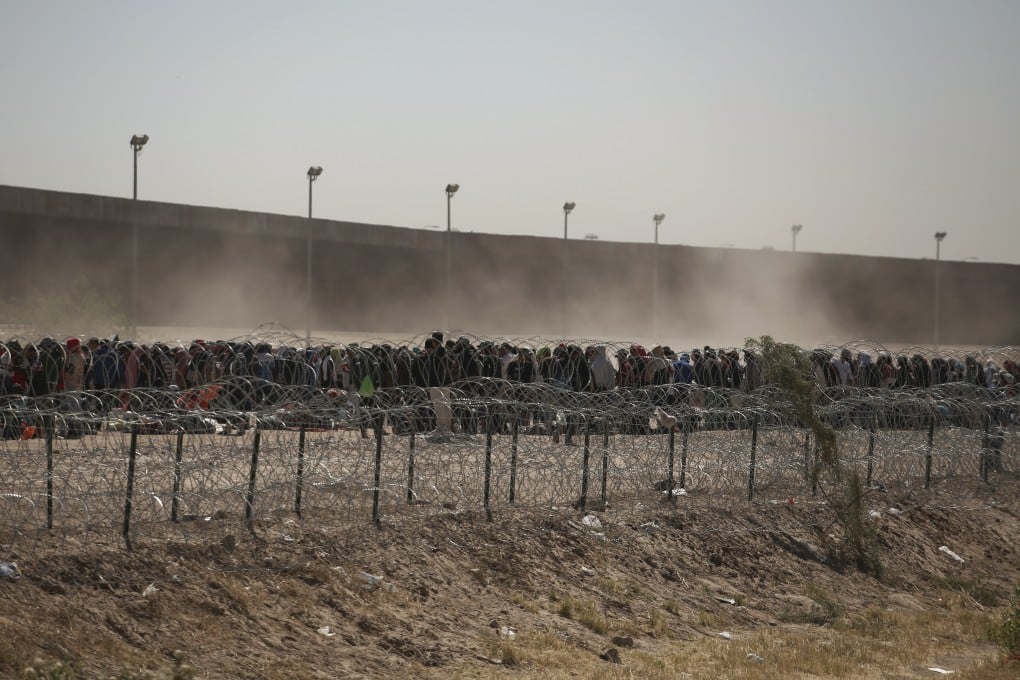 Migrants line up between a barbed-wire barrier and the border fence at the US-Mexico border, as seen from Ciudad Juarez, Mexico. Photo: AP