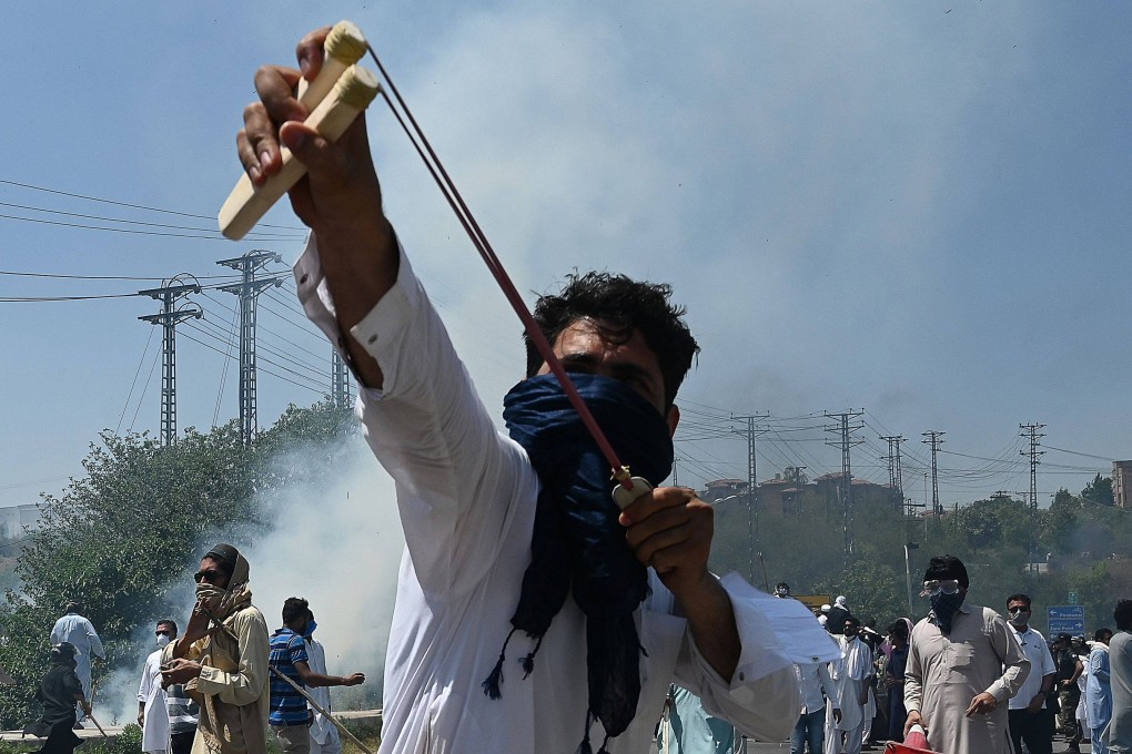 A Pakistan Tehreek-e-Insaf (PTI) party activist and supporter of former Pakistan’s Prime Minister Imran Khan uses a slingshot to throw a stone at police during a protest against the arrest of their leader. Photo: AFP
