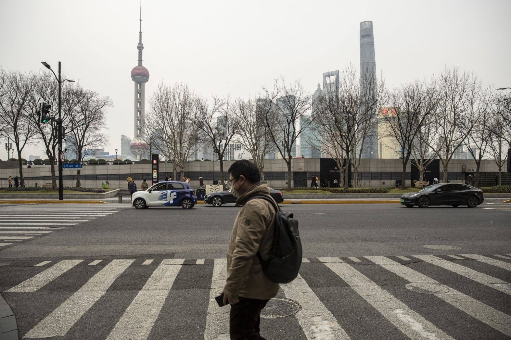 A pedestrian crosses a street near the Bund in Shanghai, across from buildings in Pudong. Police visited the Shanghai offices of Bain & Company to question its employees in April. Photo: Bloomberg