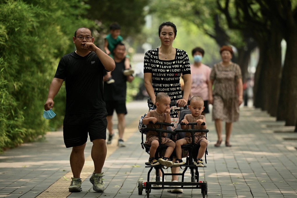 A woman pushes twins in a pram along a street in Beijing on August 16, 2022. China announced a slew of perks aimed at encouraging families to have more babies, as birth rates hit a record low. Photo: AFP