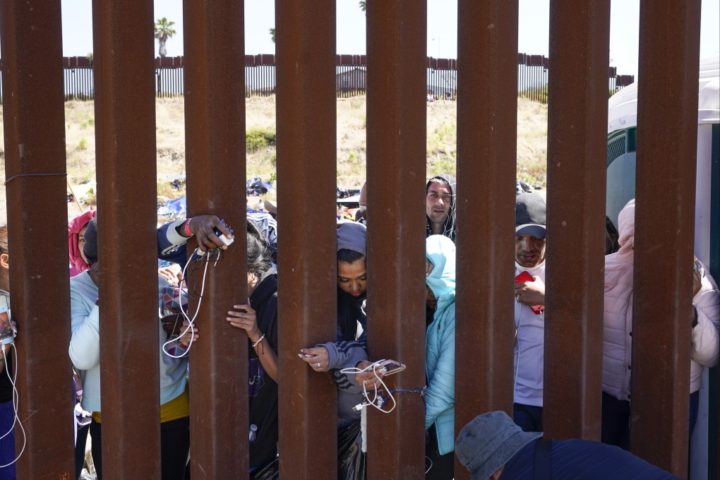 Migrants wait between two border walls to apply for asylum in San Diego on Thursday. Photo: AP