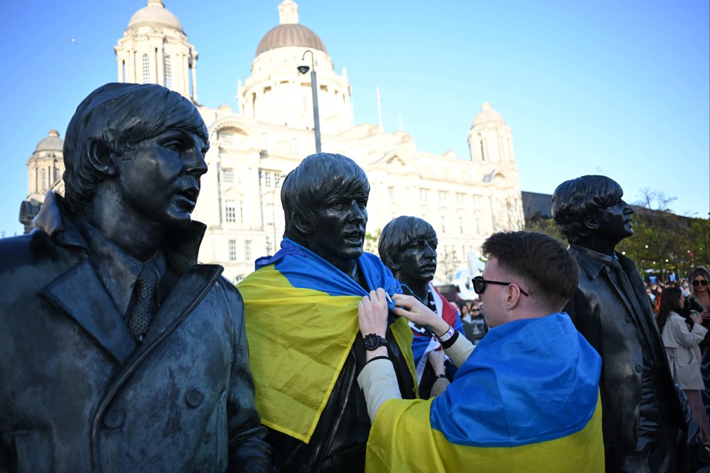 A Ukrainian man puts a flag on The Beatles statue ahead of the Eurovision Song contest being held in Liverpool, northern England. Photo: AFP