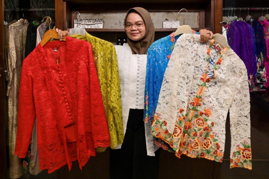 An employee poses with traditional kebayas at a shop in Jakarta. Suited to hot tropical weather, the intricately embroidered blouse is usually long-sleeved, and ranges from loose-fitting to semi-transparent, figure-hugging cuts. Photo: AFP