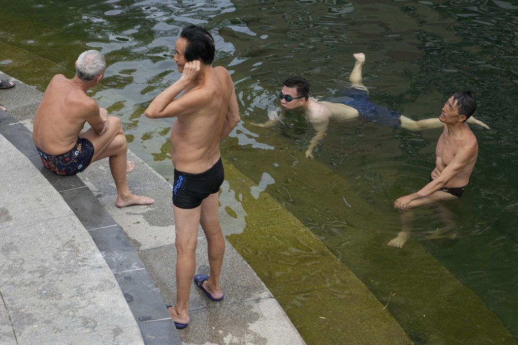 On Tuesday, May 16, residents cool off along a canal during a heat wave in Beijing. Photo: AP Photo