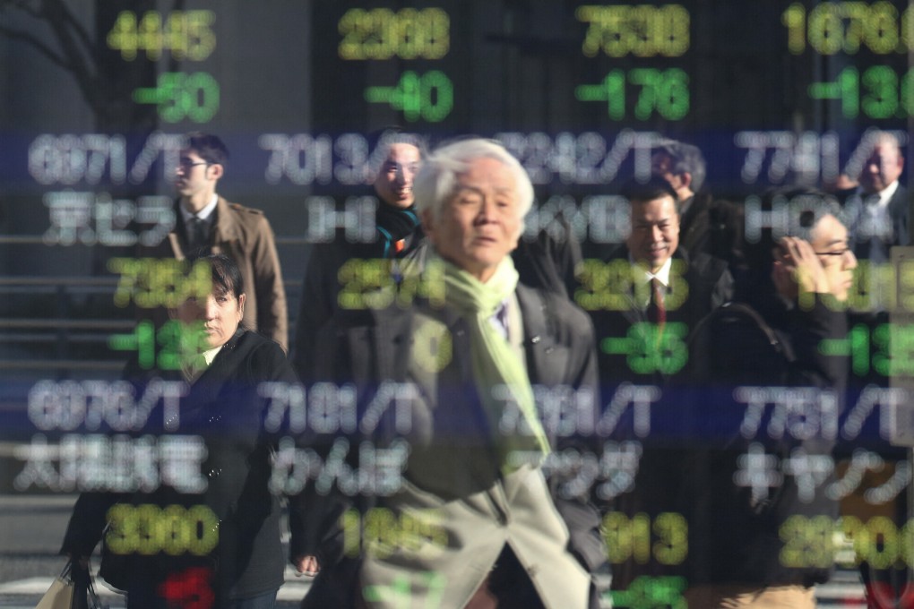 An elderly man is seen reflected in a stock indicator showing share prices of Japanese companies in Tokyo. M&A Research Institute aims to help the ageing owners of small and medium-sized businesses find successors. Photo: AFP
