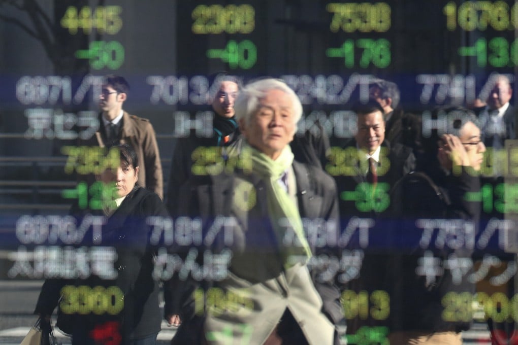 An elderly man is seen reflected in a stock indicator showing share prices of Japanese companies in Tokyo. M&A Research Institute aims to help the ageing owners of small and medium-sized businesses find successors. Photo: AFP