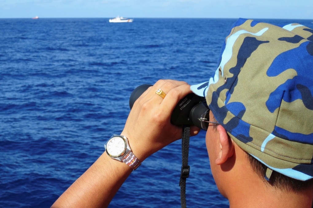 A crewman from a Vietnamese coastguard ship ooks out at Chinese coastguard vessels. Photo: Reuters
