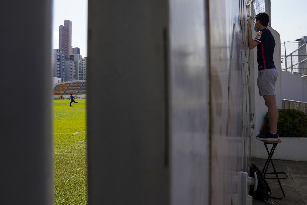 A football fan tries to get a glimpse of a closed-door match at Mong Kok Stadium in October 2020, during the pandemic. Though no longer in its heyday, Hong Kong football still draws some diehard fans. Photo: Sam Tsang