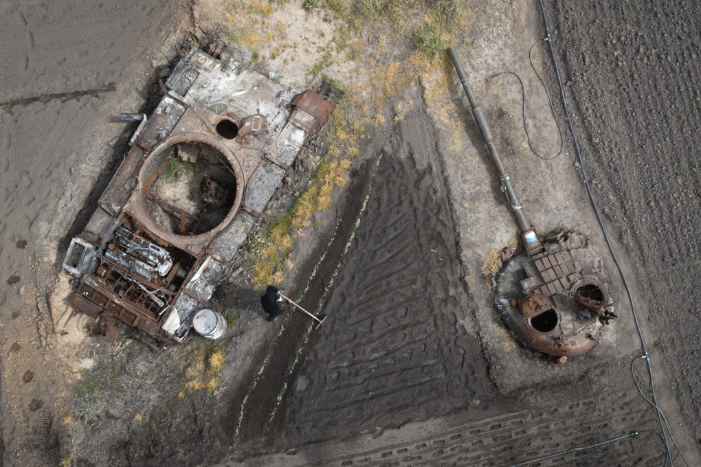 A man plants sunflowers near a destroyed Russian tank in the village of Velyka Dymerka, Kyiv region, Ukraine. Photo: AP