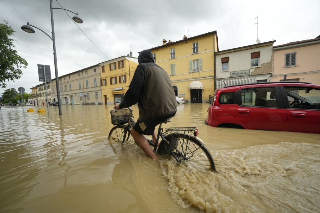 A cyclist rides through a flooded street in the Italian village of Castel Bolognese, on Wednesday. Photo: AP