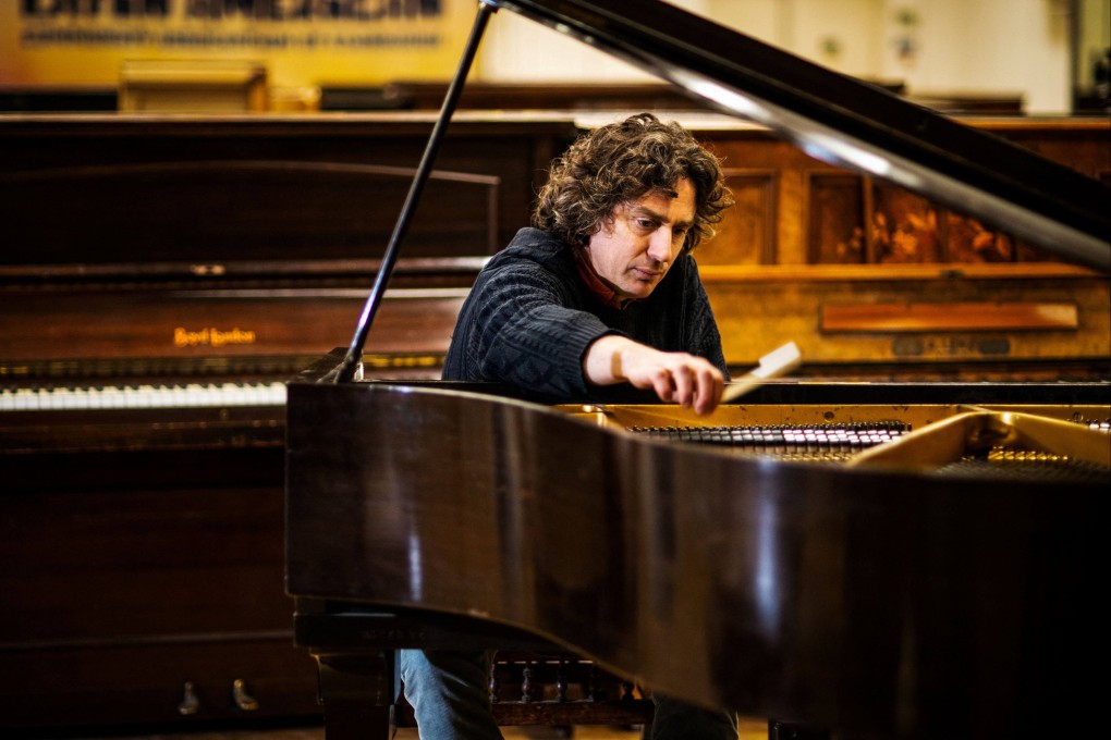 Artist and musician Tim Vincent-Smith, co-director of Pianodrome, a charity centre aiming a the refurbishing and repairing pianos, tests a piano in their atelier in a former department store near the port of Leith, in Edinburgh, Scotland. Photo: AFP