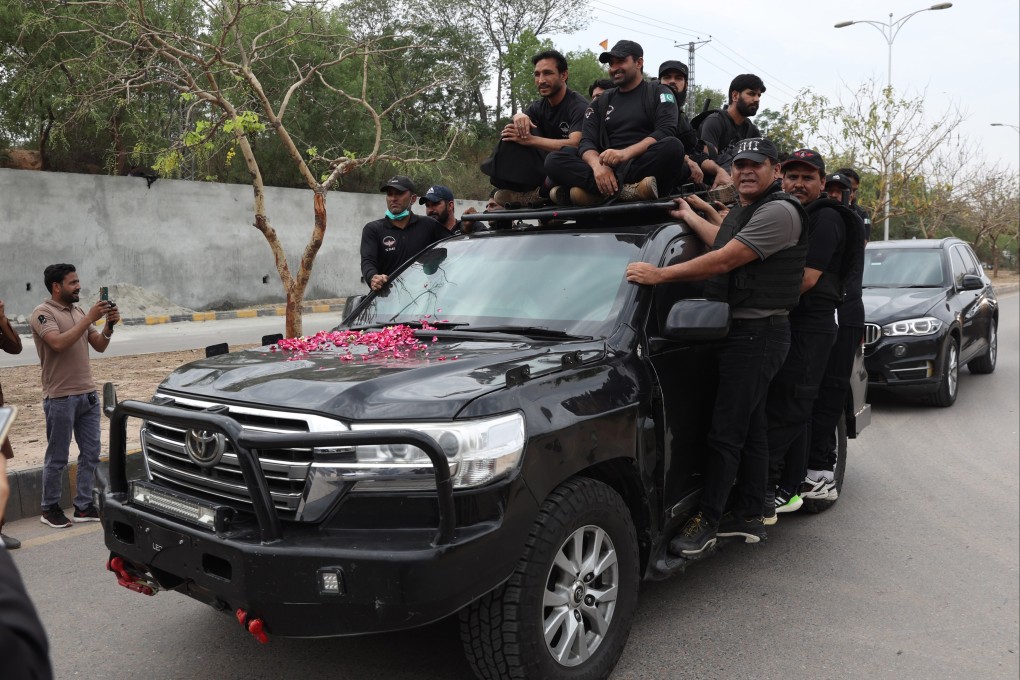 Private security personnel escort a vehicle transporting former Prime Minister Imran Khan to court to get bail on Tuesday in cases related to the violence that erupted in March between his supporters and police. Photo: EPA-EFE