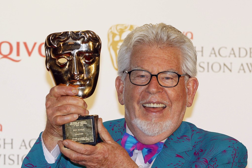 Australian entertainer Rolf Harris holds up a TV award in London in 2012. In 2014 he was convicted of abusing young girls decades before, and sent to prison. Photo: AP
