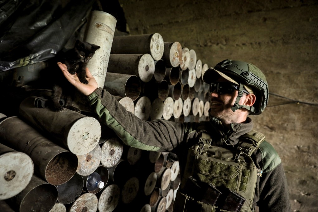 A Ukrainian soldier pets a cat next to artillery shells in the Donetsk region. Photo: EPA-EFE
