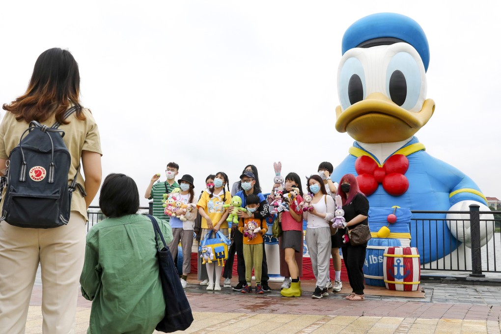 Tourists pose with an inflatable doll of Donald Duck at Wishing Star Park of Disney Resort in Shanghai. The theme park is raising ticket prices from next month. Photo: Xinhua