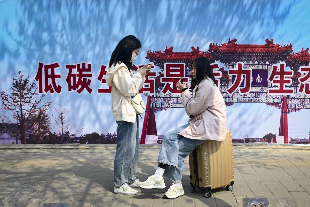 People wait at a bus stop in Beijing with a slogan promoting low-carbon living in Beijing. Photo: AFP