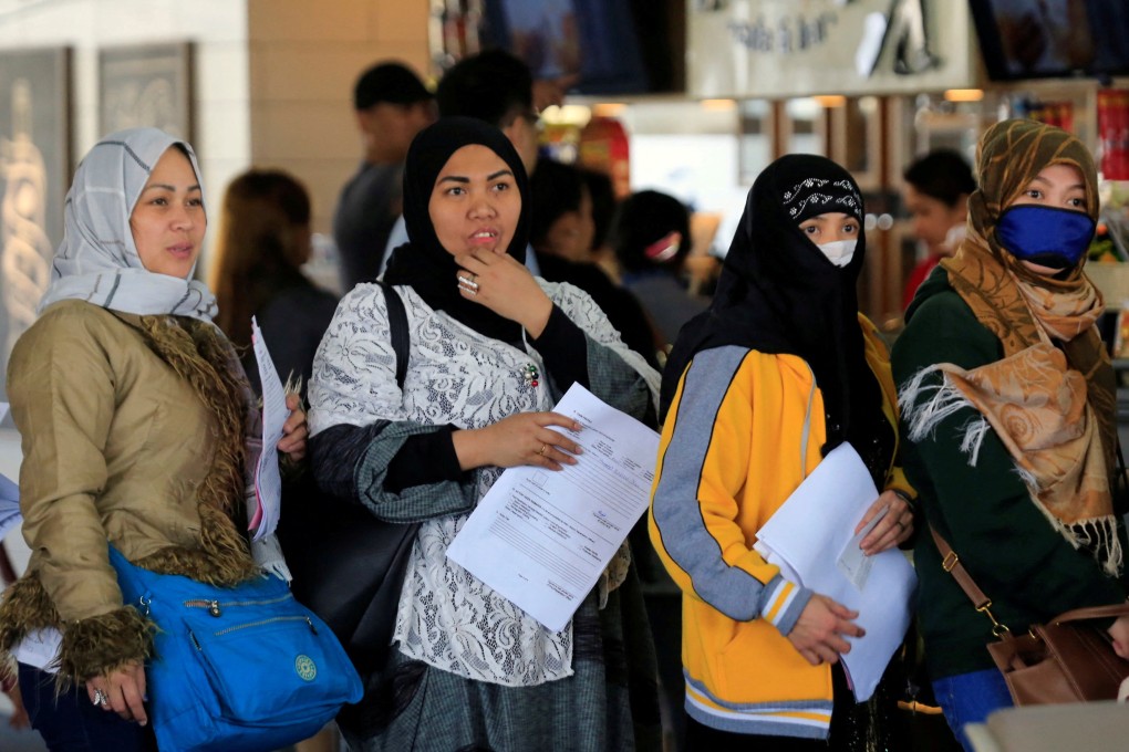 Overseas Filipino Workers from Kuwait hold their documents as they queue at the airport in Manila. Photo: Reuters