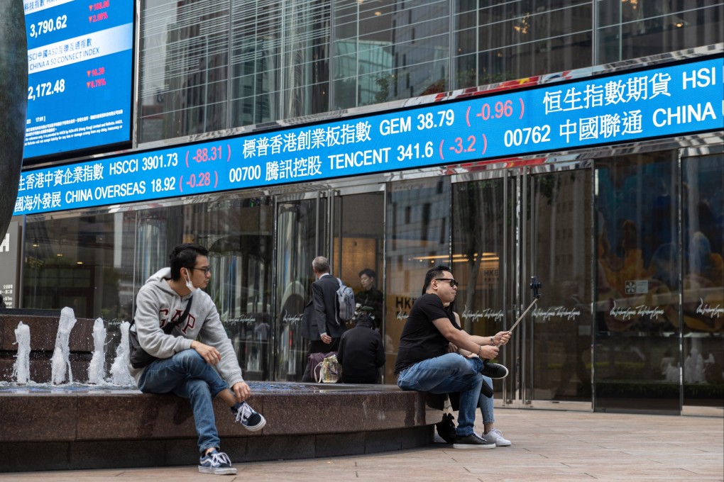 People relax near a stock ticker outside Exchange Square, the building housing the stock exchange in Hong Kong, on March 14, 2023. Photo: EPA-EFE