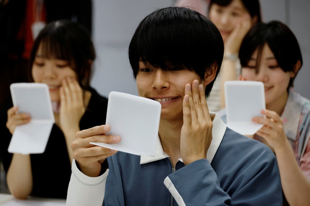 Students at a smile training course at Sokei Art School in Tokyo practice moving their facial muscles using mirrors. Photo: Reuters