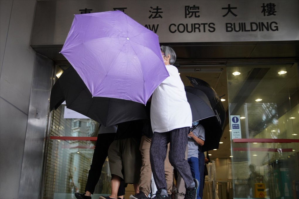 Supporters use umbrellas to shield Kwong Yiu-man (khaki trousers) at Eastern Court in Sai Wan Ho in 2020. Photo: Winson Wong