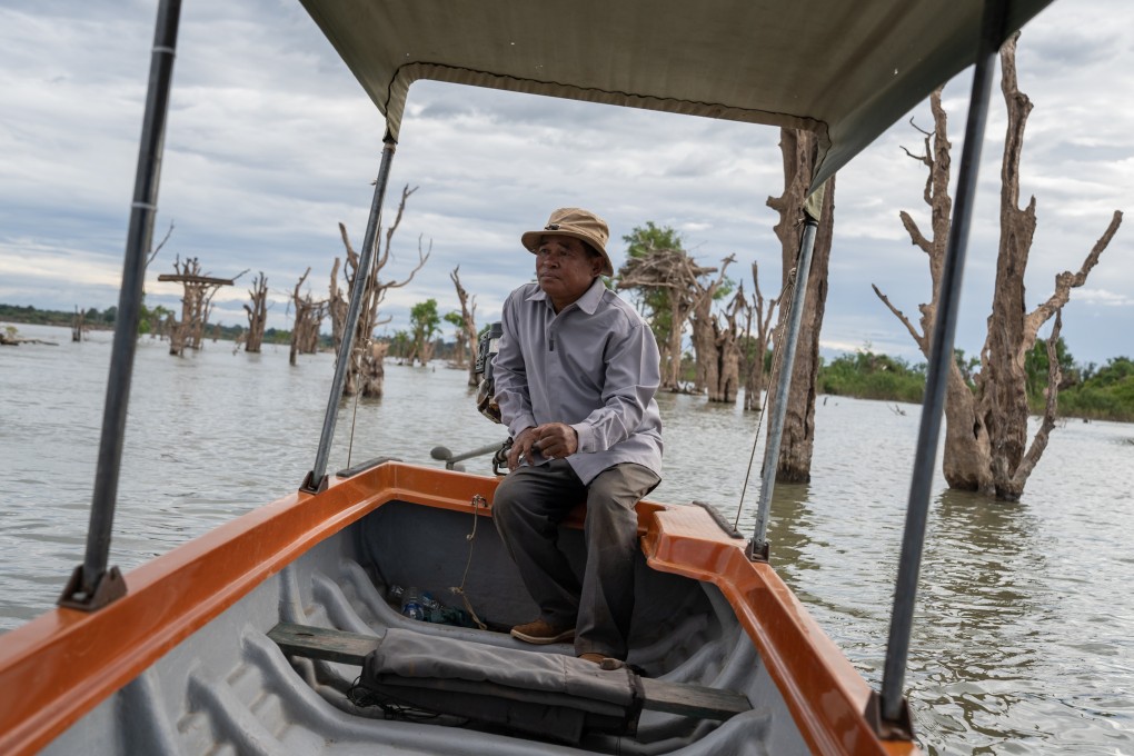 Phoy Vanna, chief of the Preah Rumkel Community-Based Ecotourism Site, drives his boat on the Mekong River through a section of dead trees that previously made up a flooded forest, in Stung Treng Ramsar Site, Stung Treng province, Cambodia, on December 6, 2022. Photo: Andy Ball