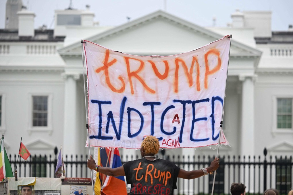 A woman celebrating the federal indictment of former US president Donald Trump holds a banner in front of the White House in Washington on Friday. Photo: AFP