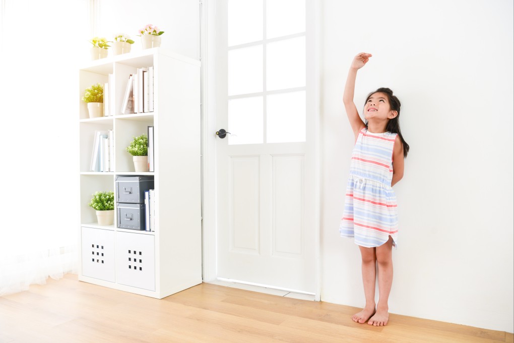 A girl uses her hand to measure her height. Average heights in several nations have both risen and fallen over recent decades. Photo: Shutterstock