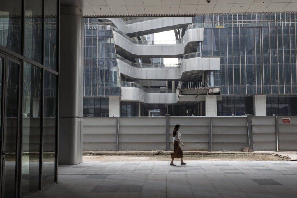 A pedestrian passes a construction site for a commercial building in the Pazhou area of Guangzhou, China. Photo: Bloomberg