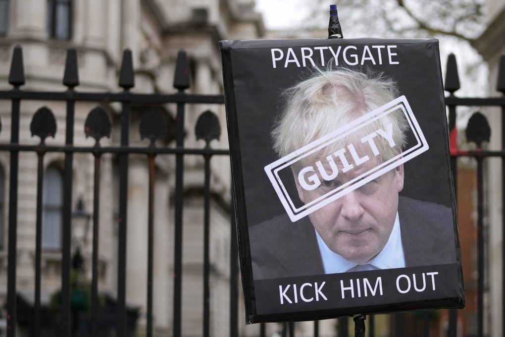 A protester holds a sign in front of the entrance to Downing Street former showing British Prime Minister Boris Johnson. Photo: AP
