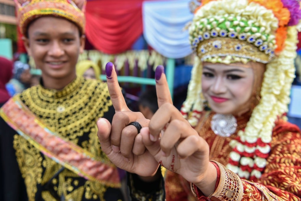 Indonesians show their inked fingers after voting on April 17, 2019. Indonesia’s current open list proportional voting system means that voters can cast ballots for either an individual candidate or a party. Photo: AFP