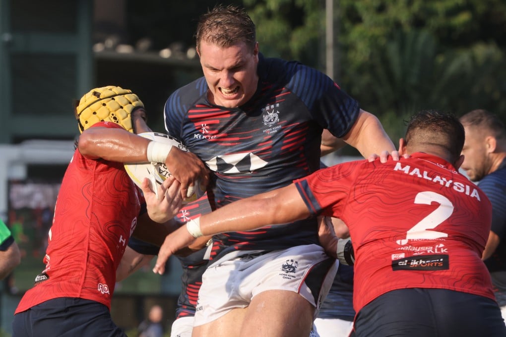 Hong Kong captain Tom Hill breaks through a double tackle from Malaysia’s Adam Arif Alias and Amirul Amizam. Photo: Jonathan Wong