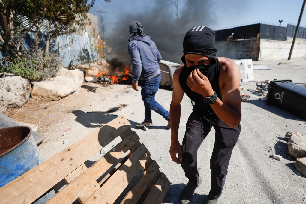A Palestinian covers his face during clashes with Israeli troops after Israeli settlers attack Umm Safa village near Ramallah, in the Israeli-occupied West Bank, on Saturday. Photo: Reuters