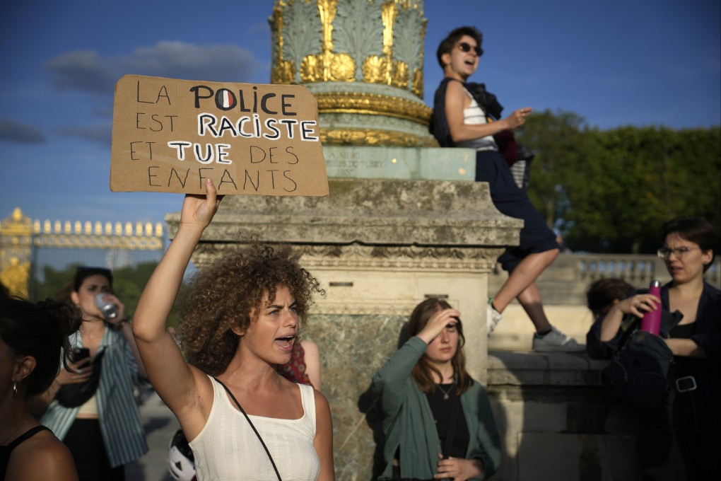 A protester holds a placard reading “Police are racist and kill children” in Paris, France on Friday. Photo: AP