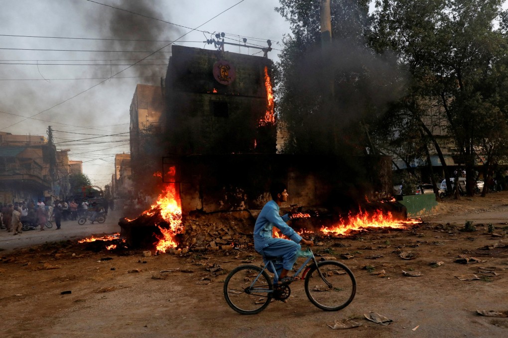 A boy rides past a paramilitary check post that was set afire by supporters of Pakistan’s former prime minister Imran Khan, during a protest against his arrest, in Karachi in May 2023. Photo: Reuters