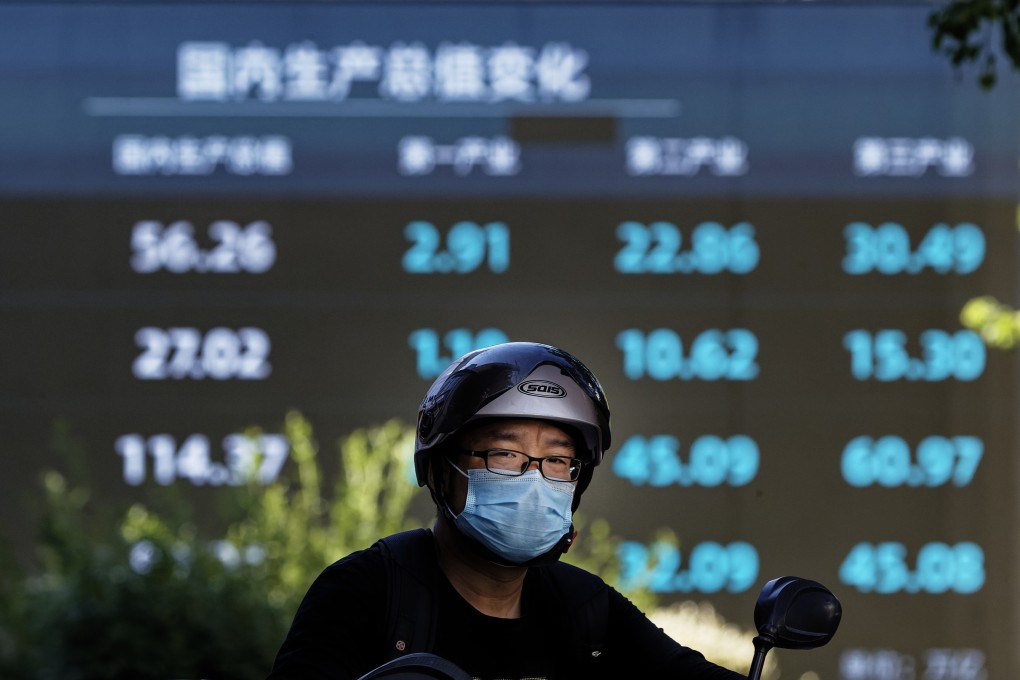A man rides a motorcycle in front of a screenshowing stock indices, in Shanghai in August 2022. Photo: EPA-EFE